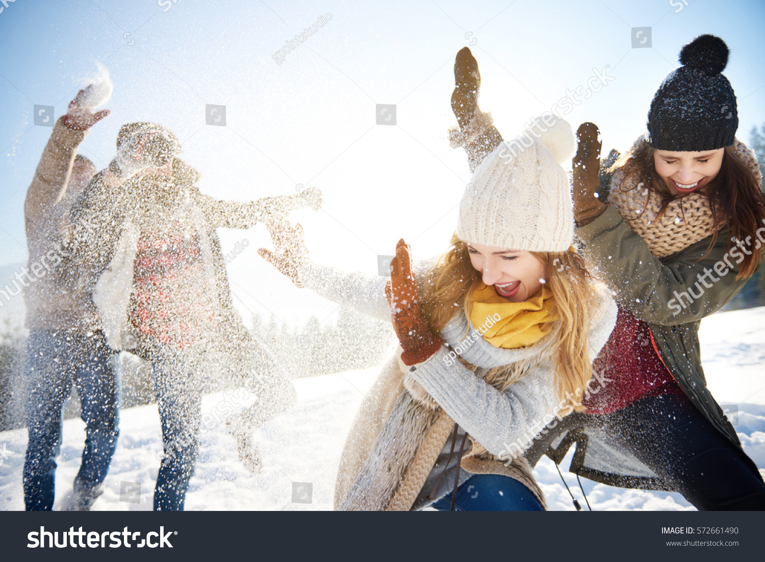 Boys throwing snowballs right on the girls