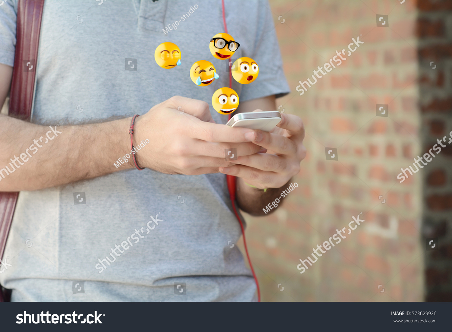 Close-up of man using smartphone sending emojis. Social concept.