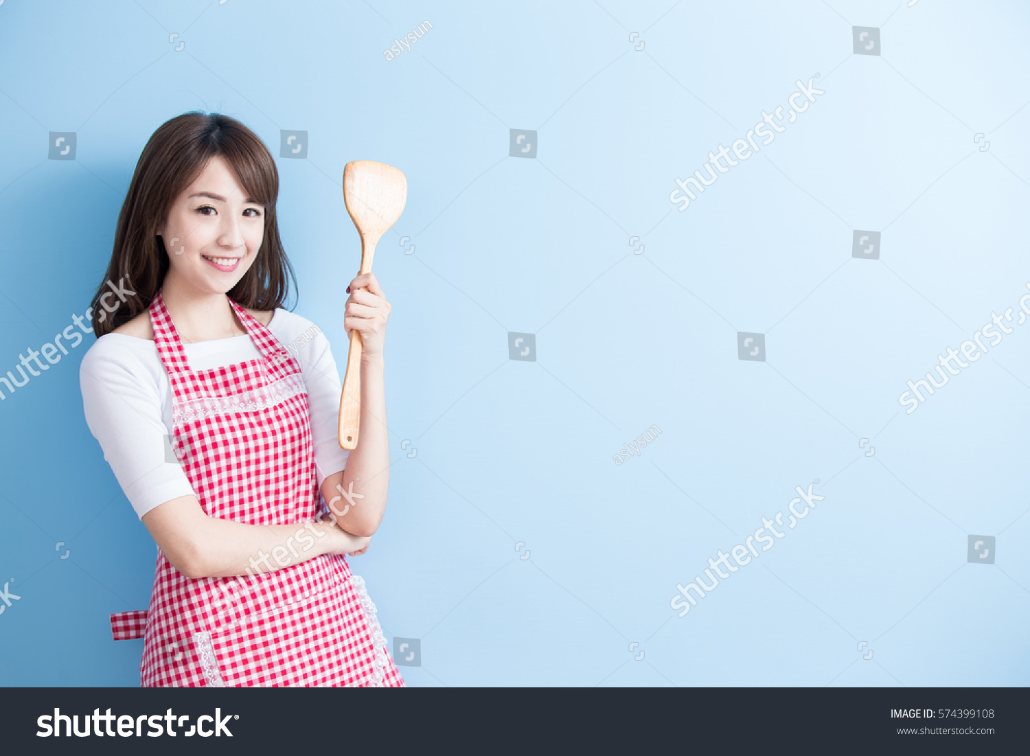 beauty housewife take rice spoon and smile isolated on blue background