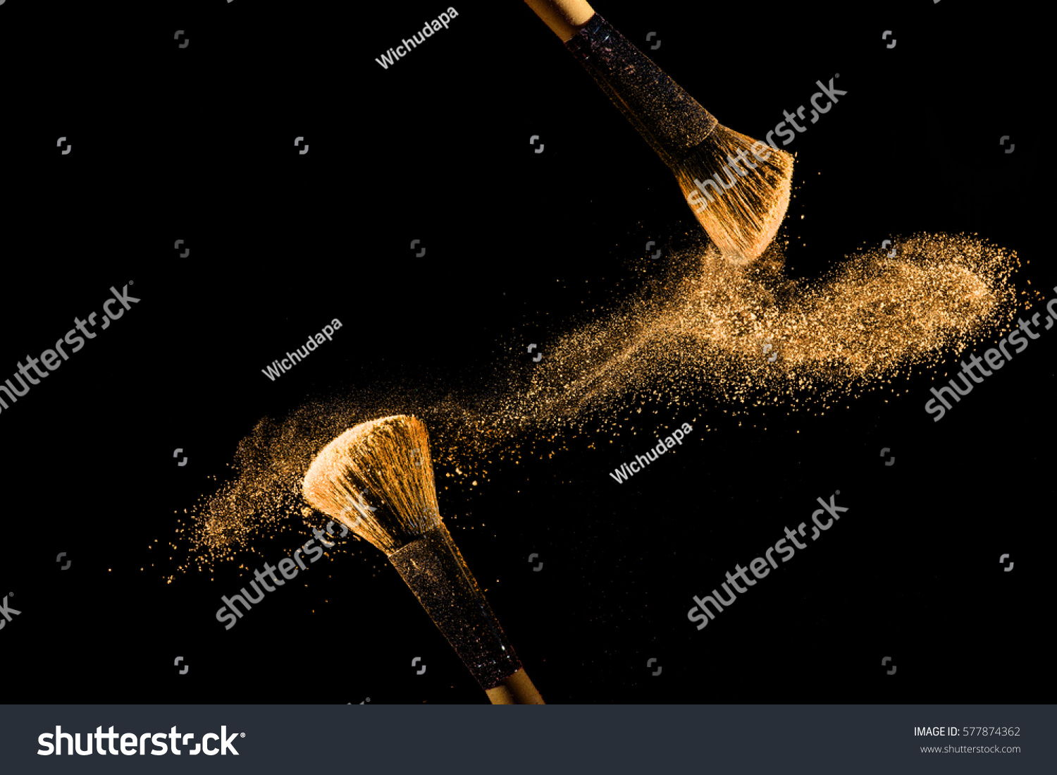 Cosmetic brush with golden cosmetic powder spreading on black background