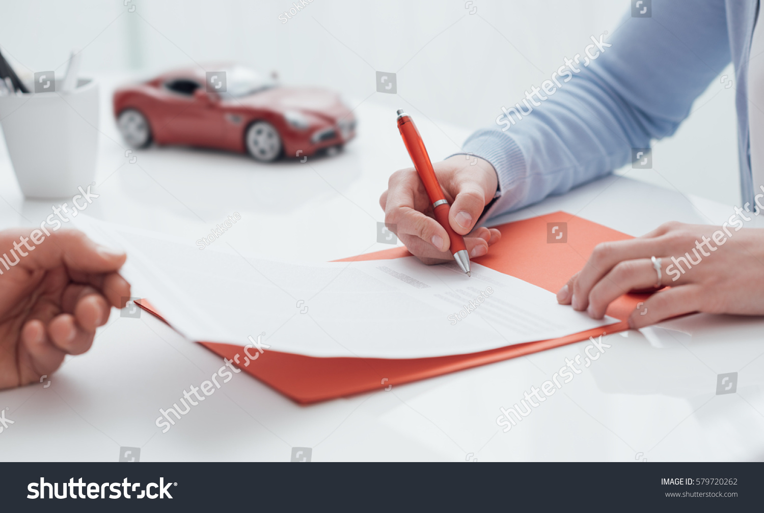 Woman signing a car insurance policy  the agent is holding the document