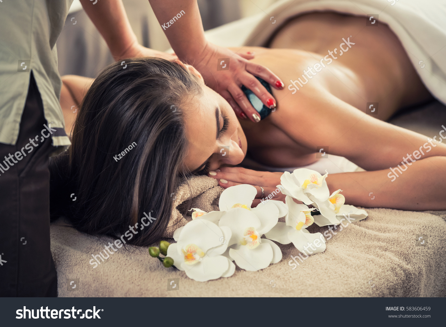 Young woman enjoying the therapeutic effects of a traditional hot stone massage at luxury spa and wellness center