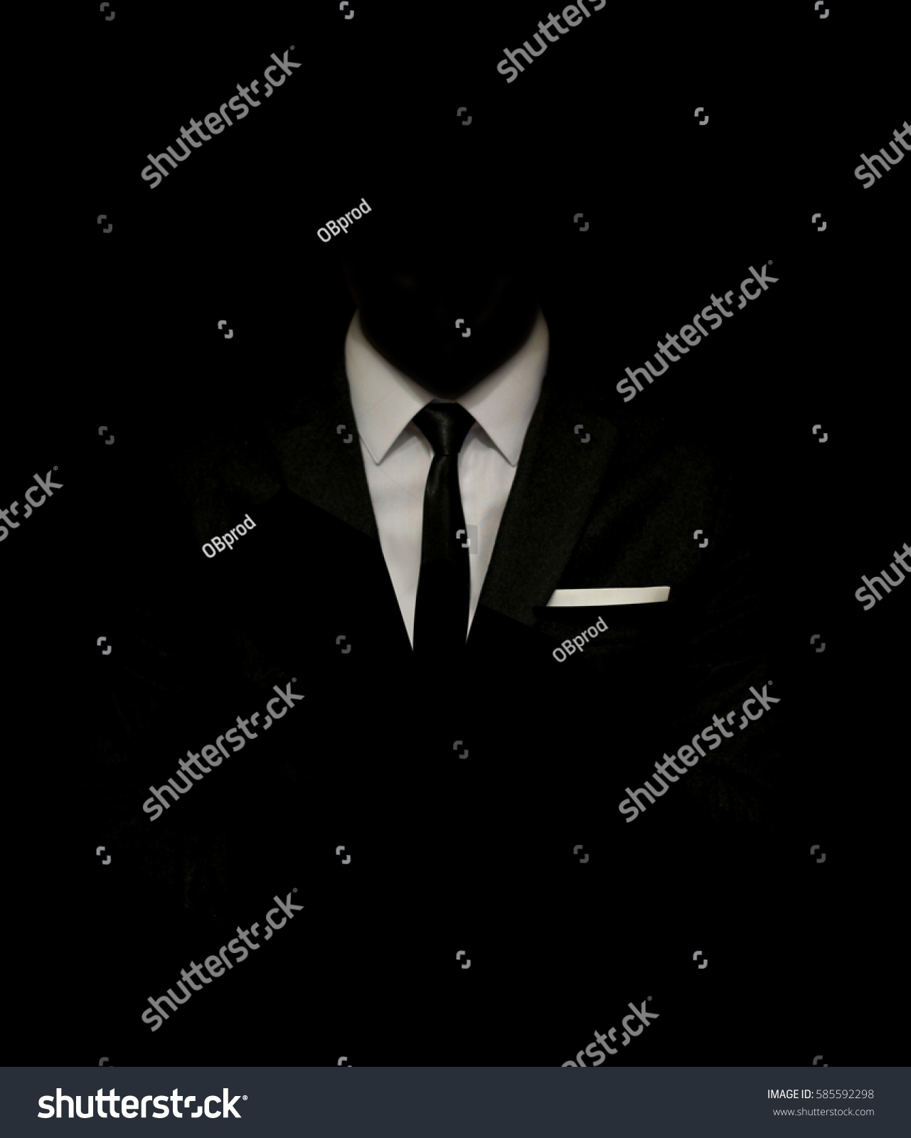 Man in a black suit and white shirt and black tie on a black background. Without a face. The businessman in the dark. Studio shot