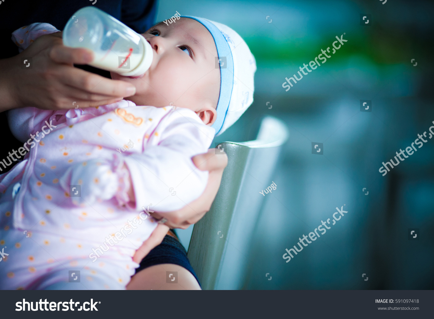 Mother is feeding her baby by using bottle.