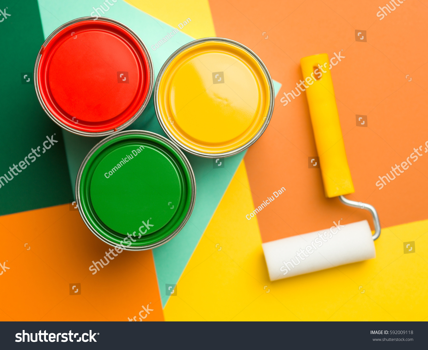 three cans  yellow green and red and paint roll on colourful geometrical background