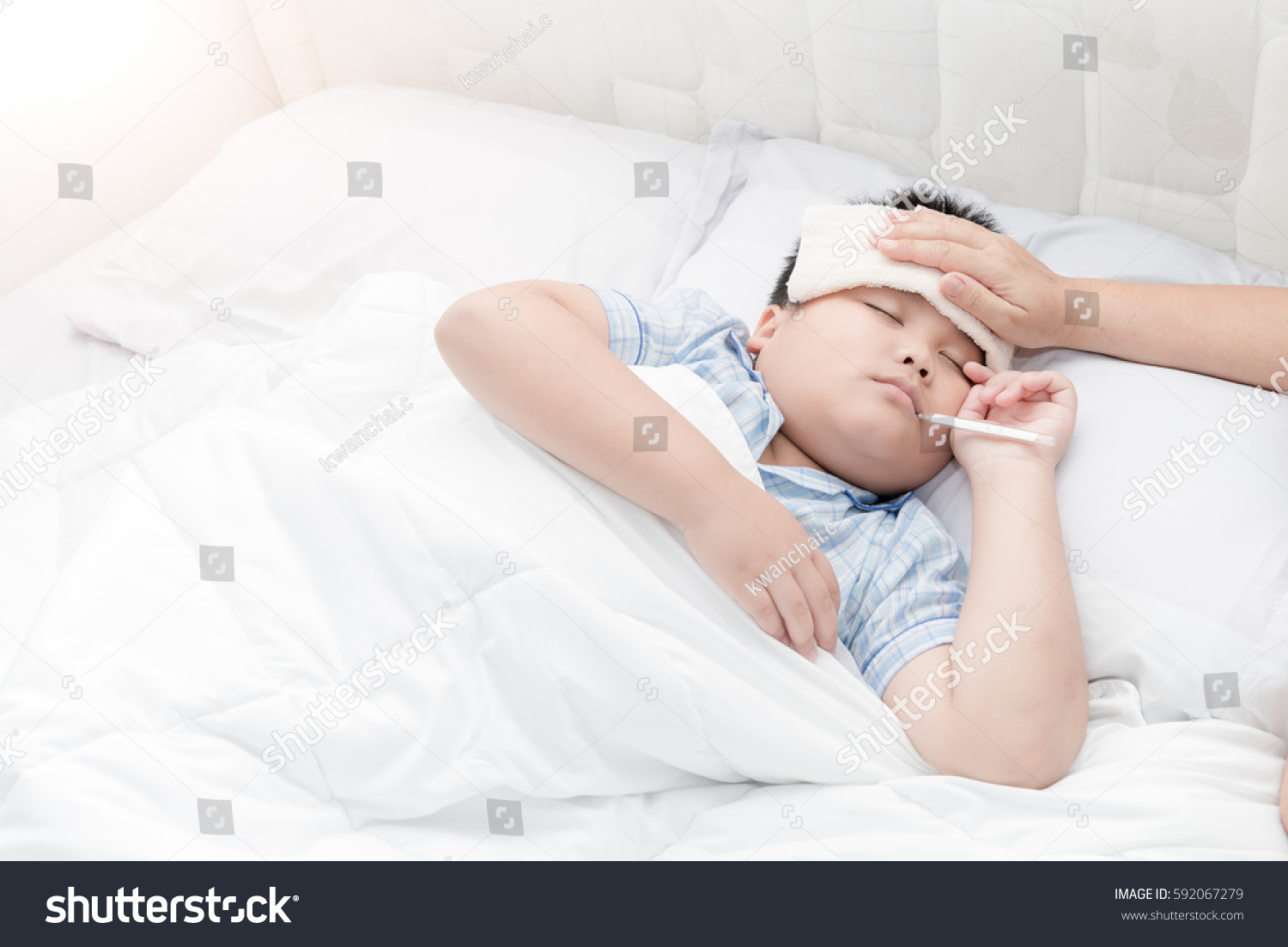 Sick boy with thermometer laying in bed and mother hand taking temperature. Sick child with fever and illness in bed