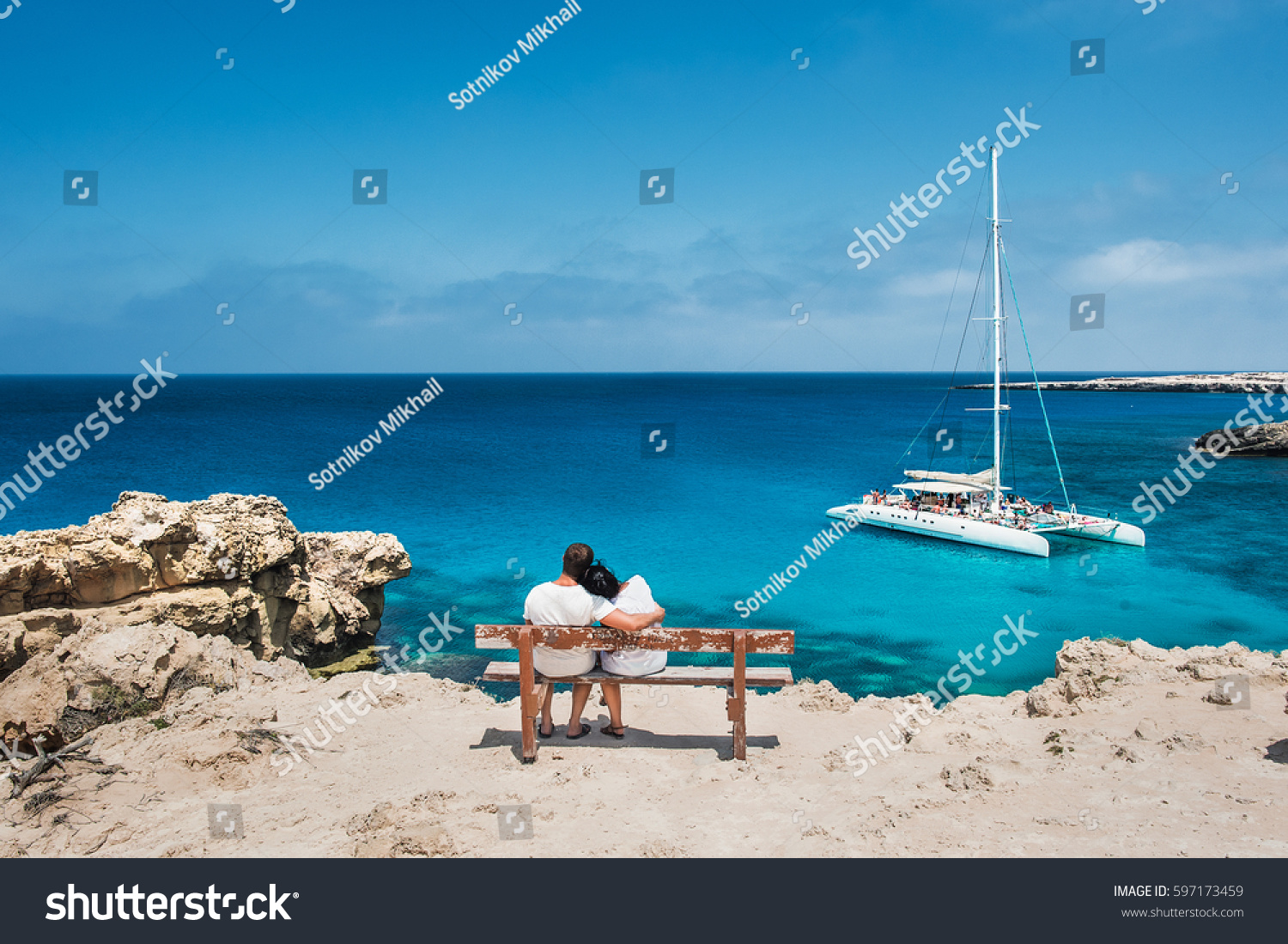 Loving couple sitting on a bench and looks at the lagoon