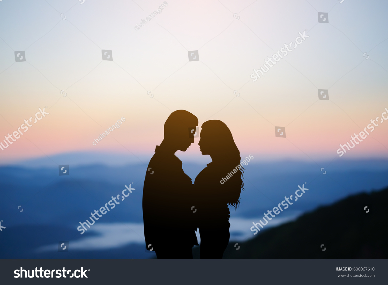 silhouette teenager lovers couple on sunset dusk sky background at the mountain