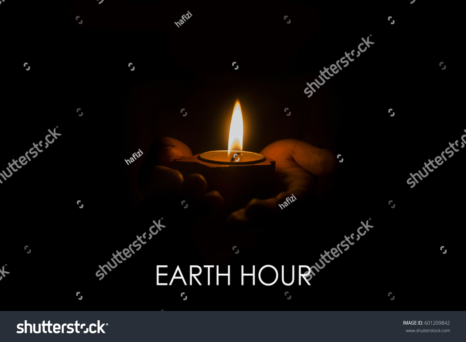 a child holds a candle in hands focus on candle with word earth hour on black background