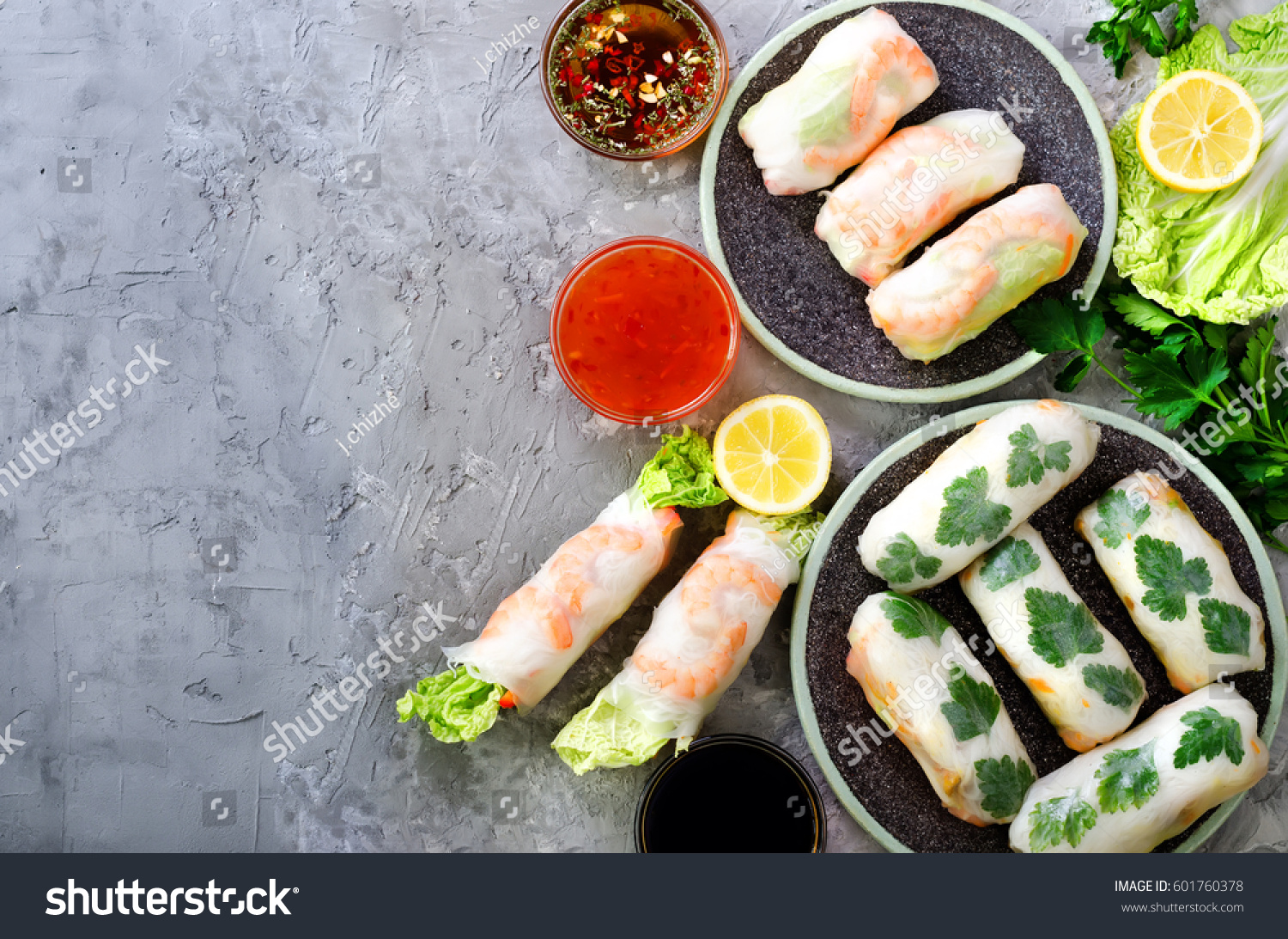 Fresh Vietnamese  Asian  Chinese food frame on grey concrete background. Spring rolls rice paper  lettuce  salad  vermicelli  noodles  shrimps  fish sauce  sweet chili  soy  lemon. Top view