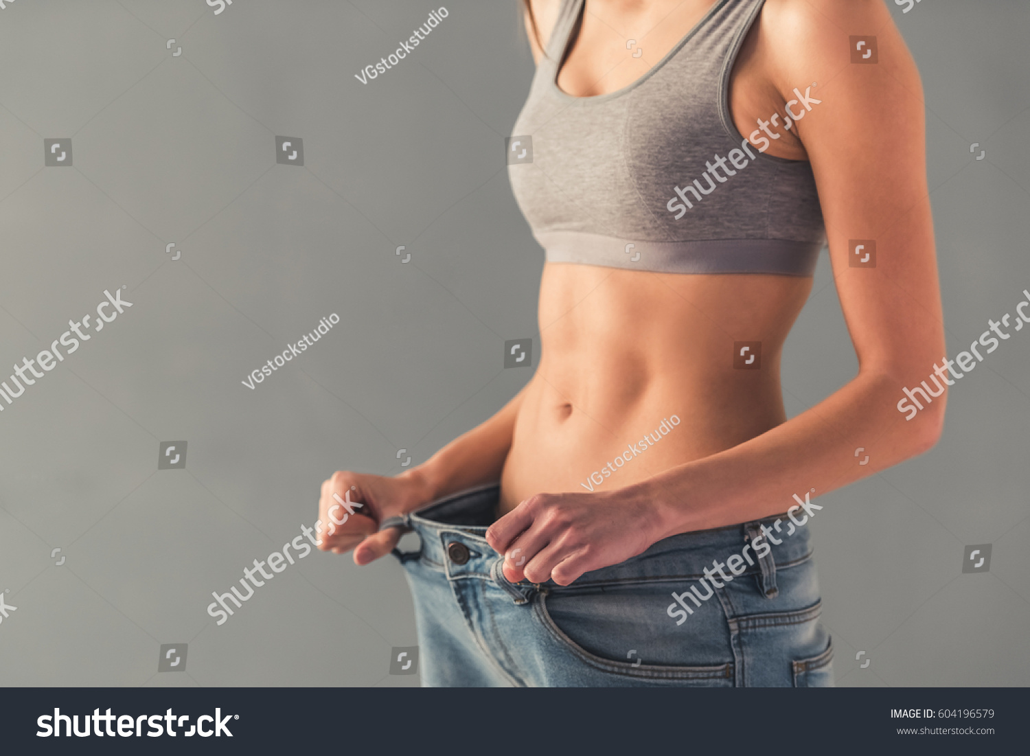 Cropped image of girl pulling her big jeans and showing weight loss