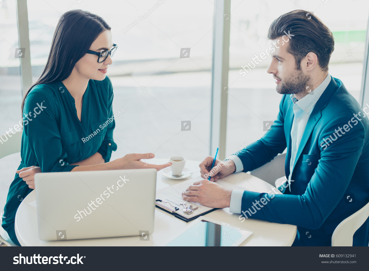 Photo of young man talking to broker and putting a signature on contract.