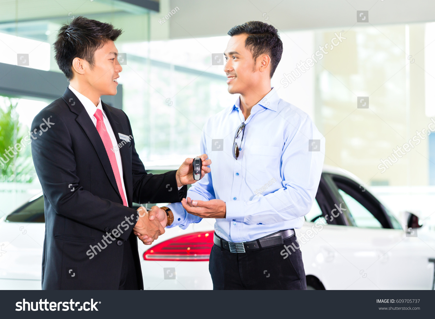 Asian Car Salesman selling auto to customer