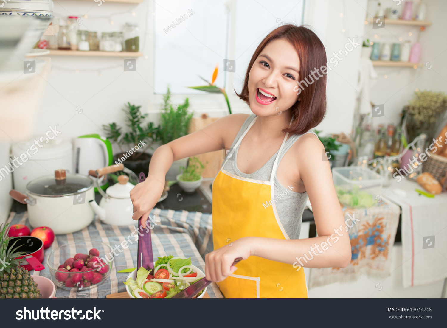 Young asian woman making salad in kitchen smiling and laughing happy at home.