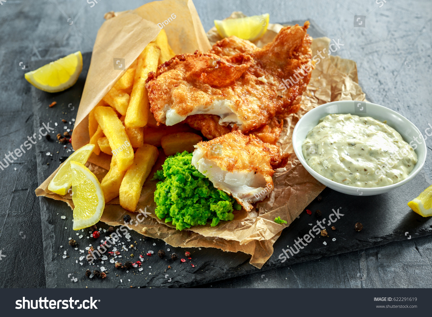 British Traditional Fish and chips with mashed peas  tartar sauce on crumpled paper.