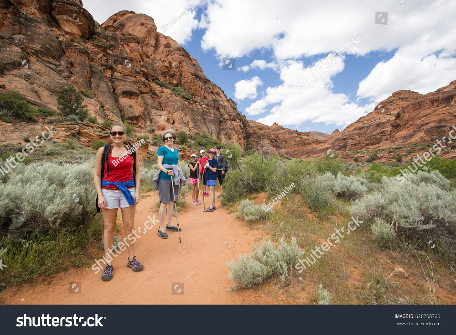 Smiling group of hikers enjoying the day hiking together along a beautiful desert cliff hiking trail in Utah. Natural beautiful in a national recreation park. 