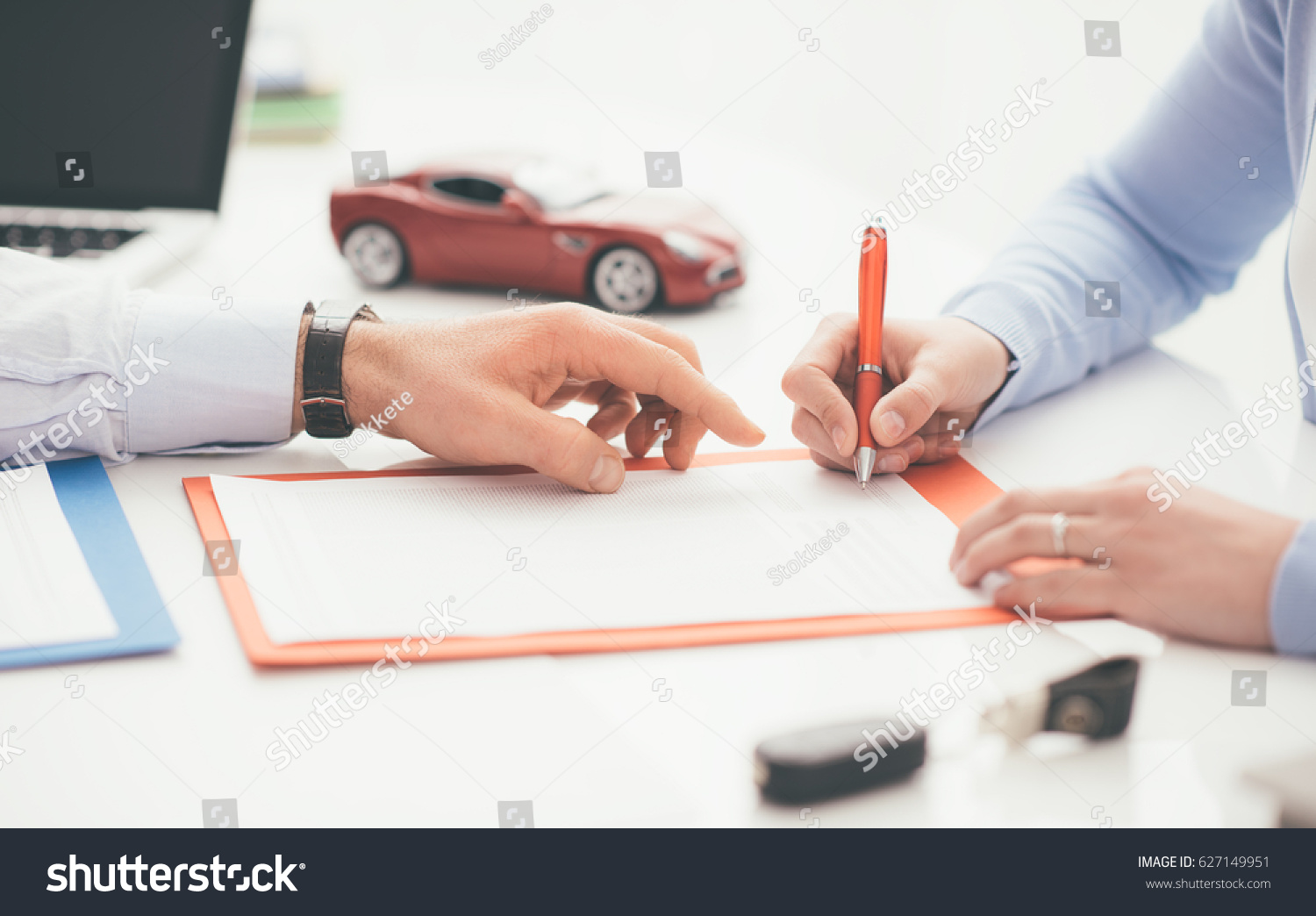 Woman signing a car insurance policy  the agent is pointing at the document