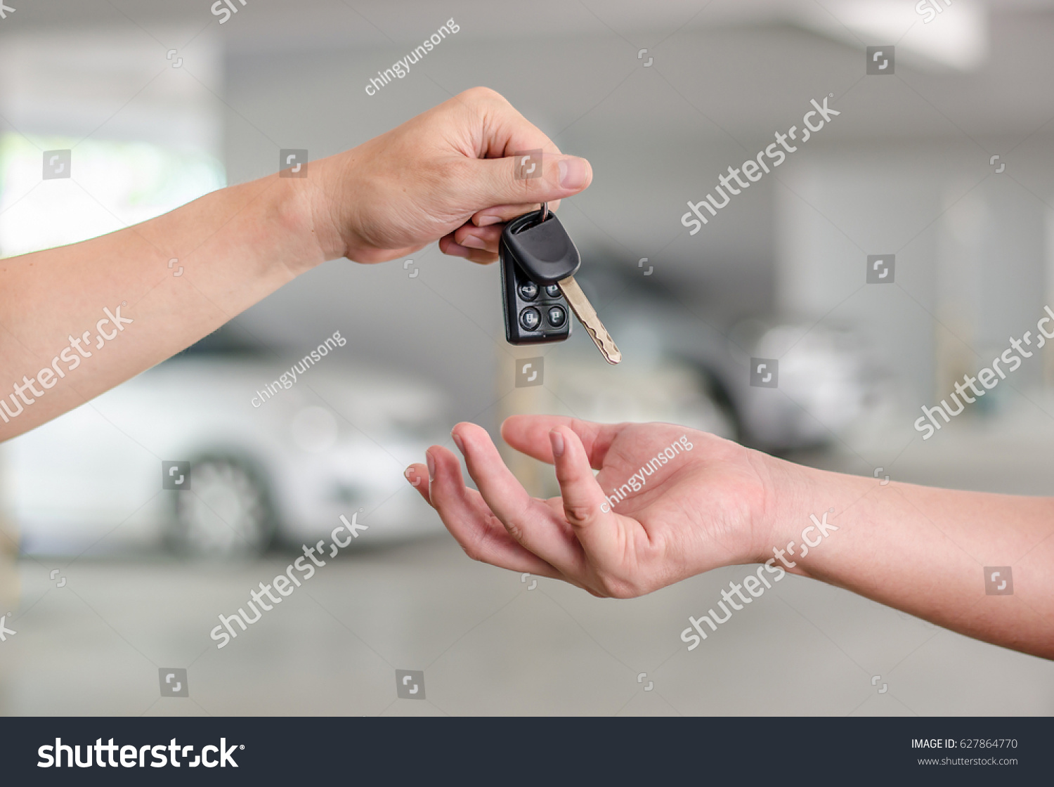 Male hand holding a car key and handing it over to another person