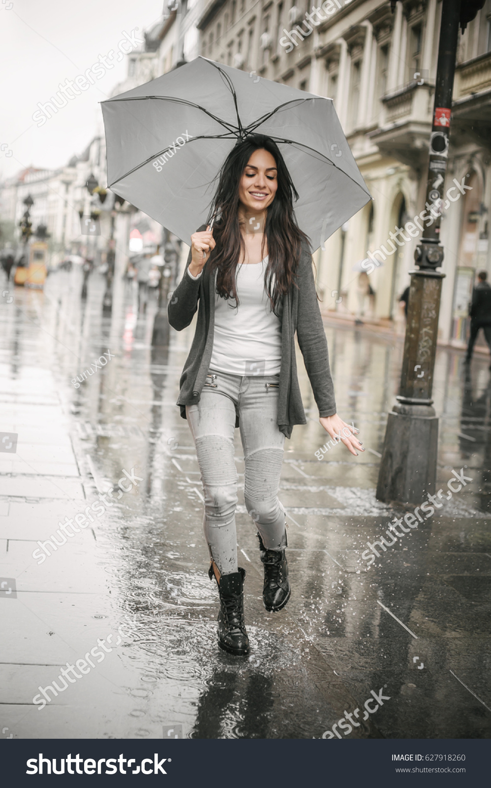 Portrait of beautiful woman dancing in the rain with umbrella  Splash in puddle