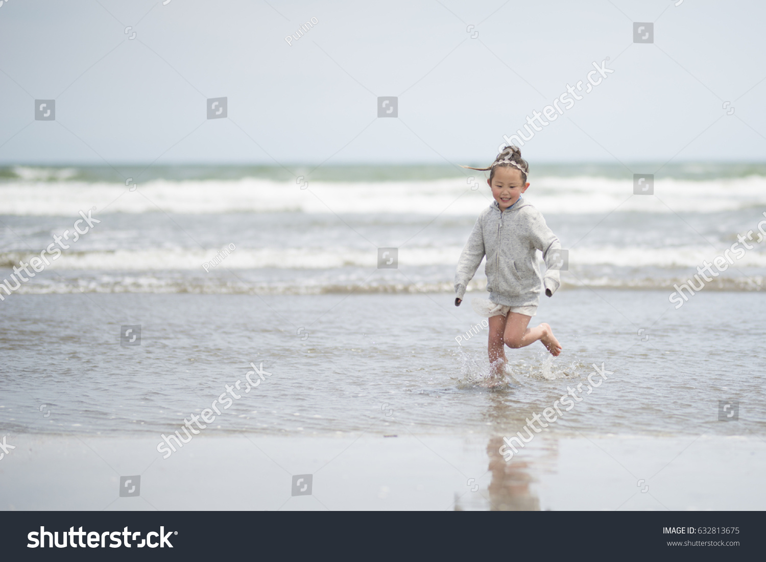 Little girl in a parka playing on the beach