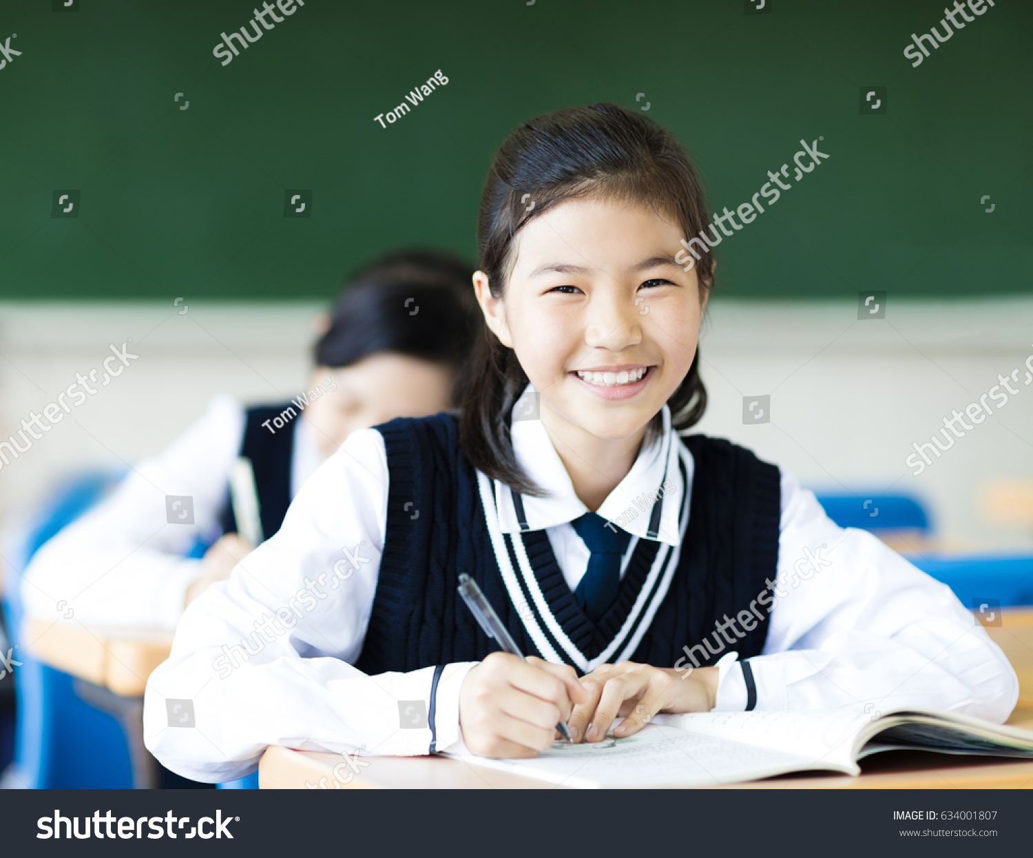 smiling student girl in classroom and her friends in background
