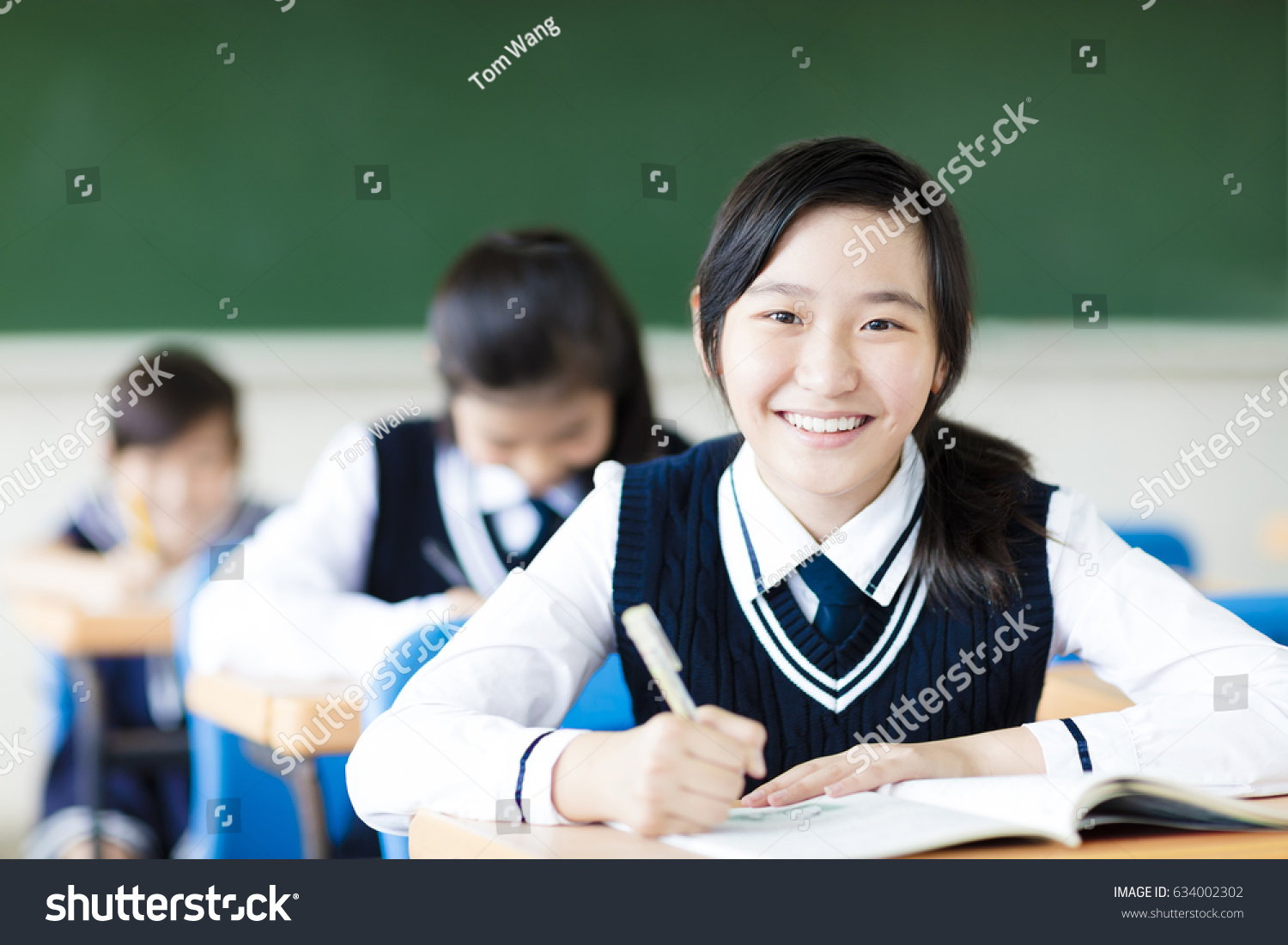 smiling student girl in classroom and her friends in background