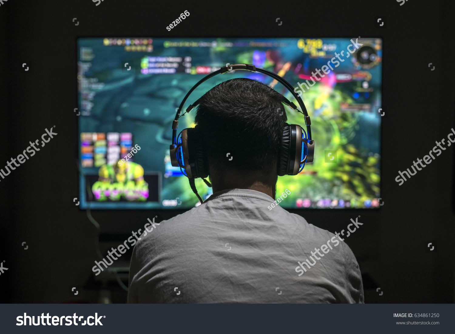 Young gamer playing video game wearing headphone.