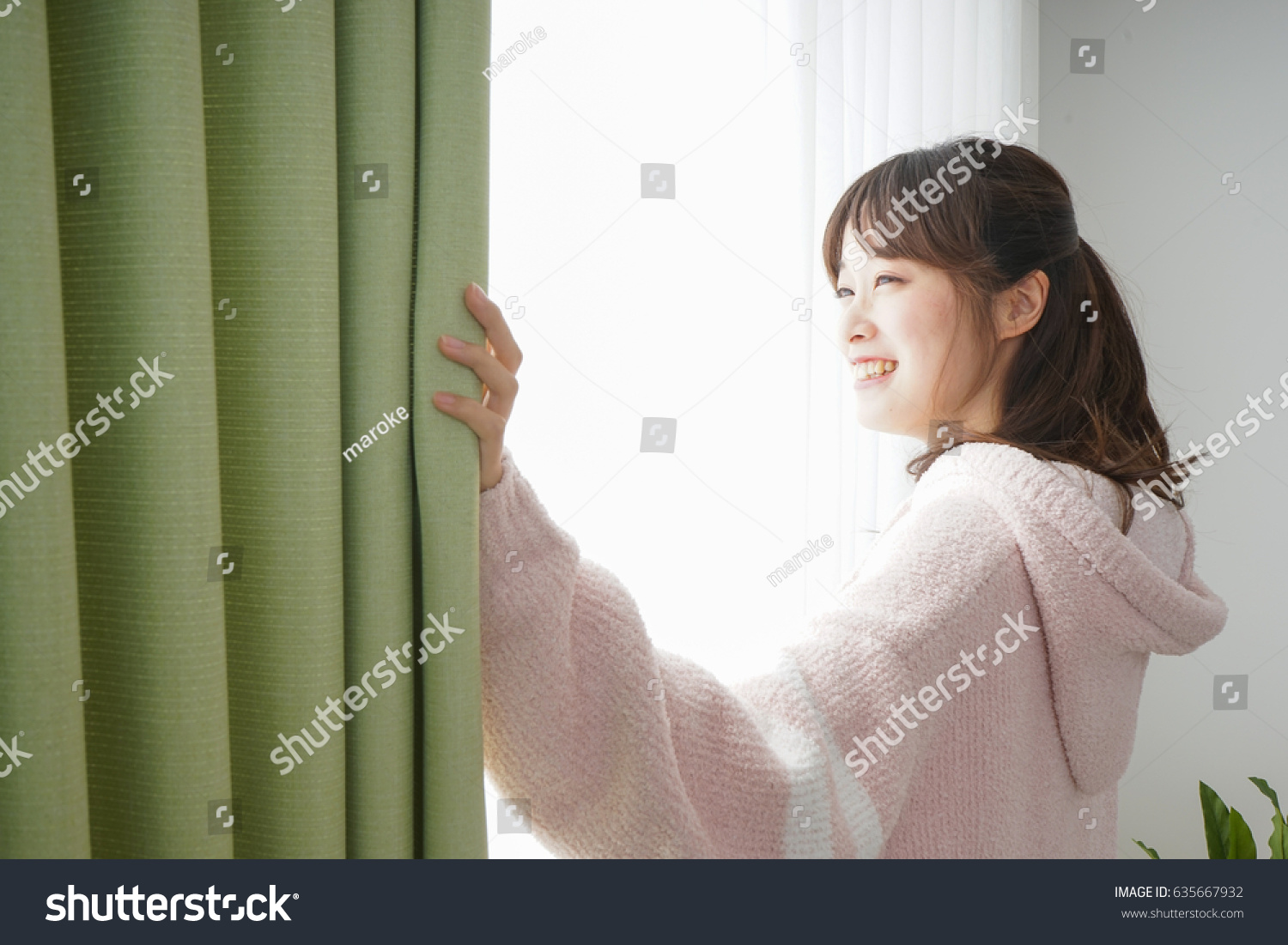 Young woman opening a curtain when getting up 