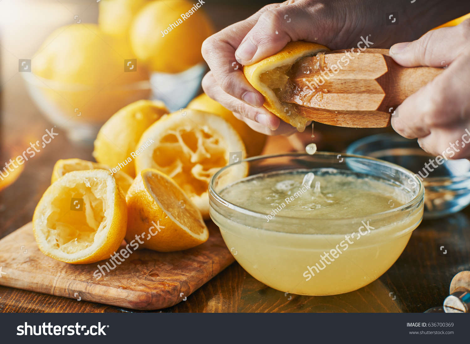 squeezing fresh lemon juice with wooden reamer into bowl