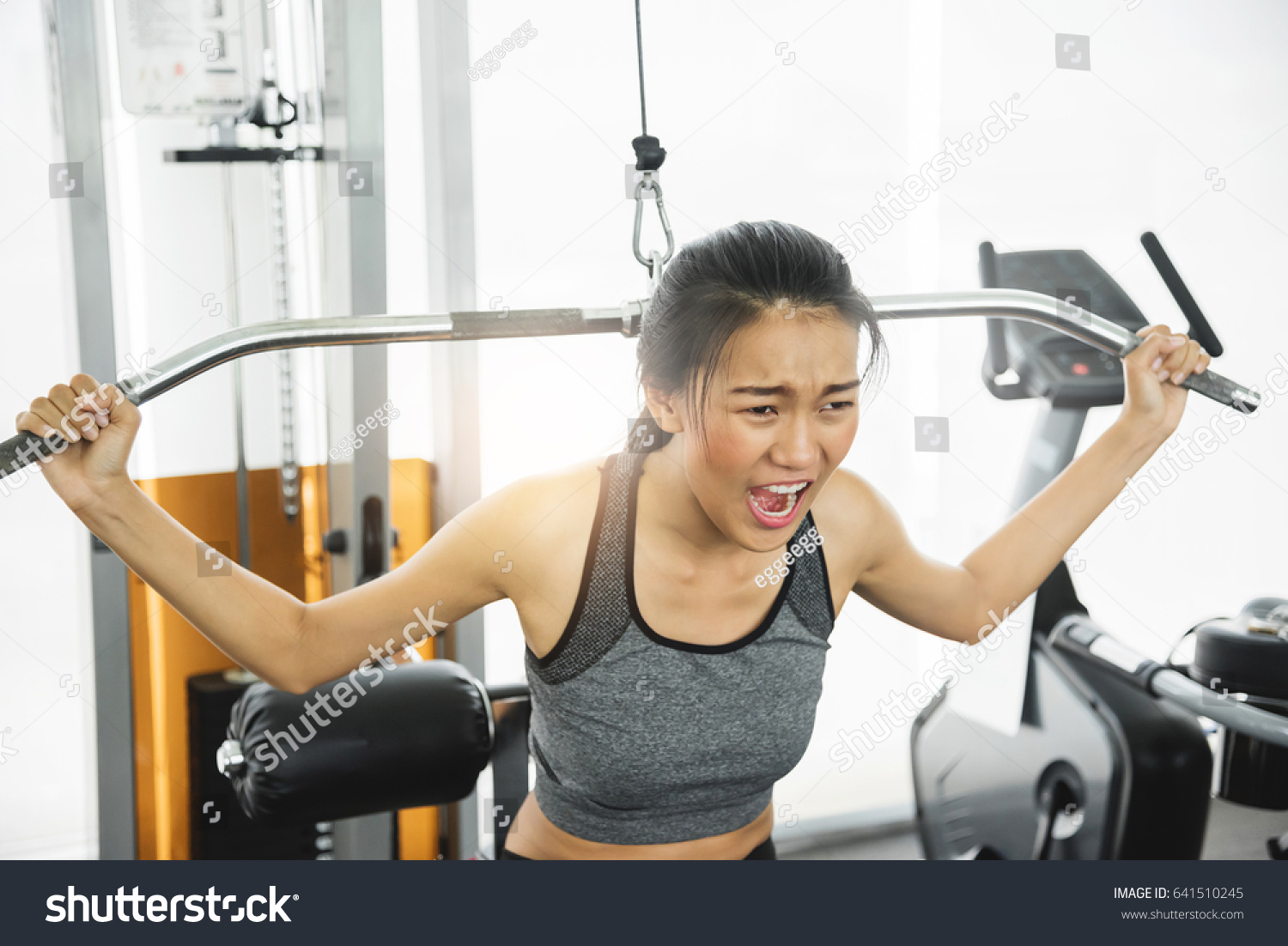 Asian woman in sportswear exercising with exercise machine at the gym.