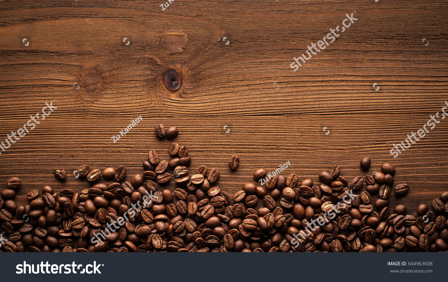 Black coffee grains lie on a brown wooden table  background image