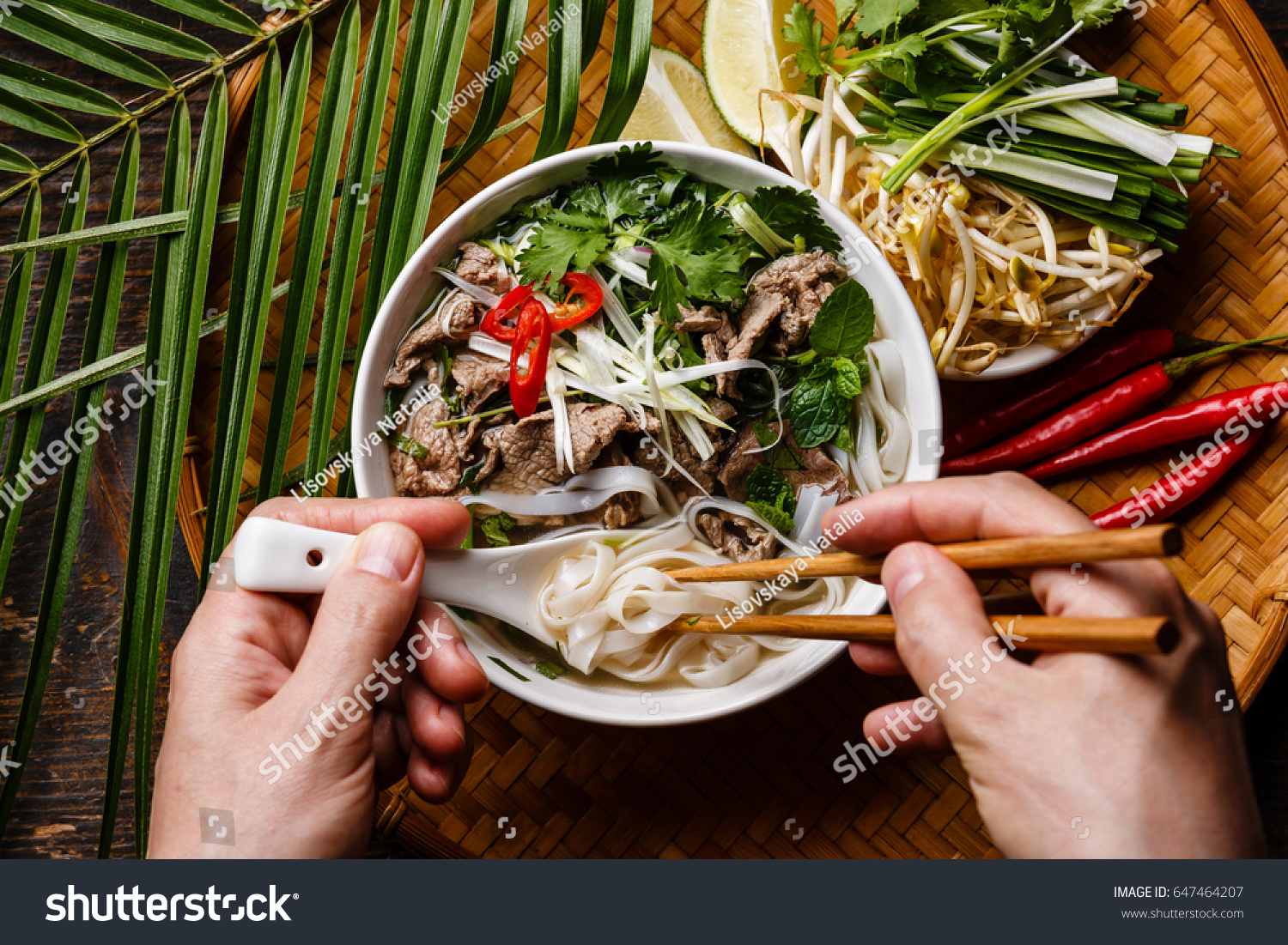 Pho Bo Soup with beef and chopsticks in male hands close-up