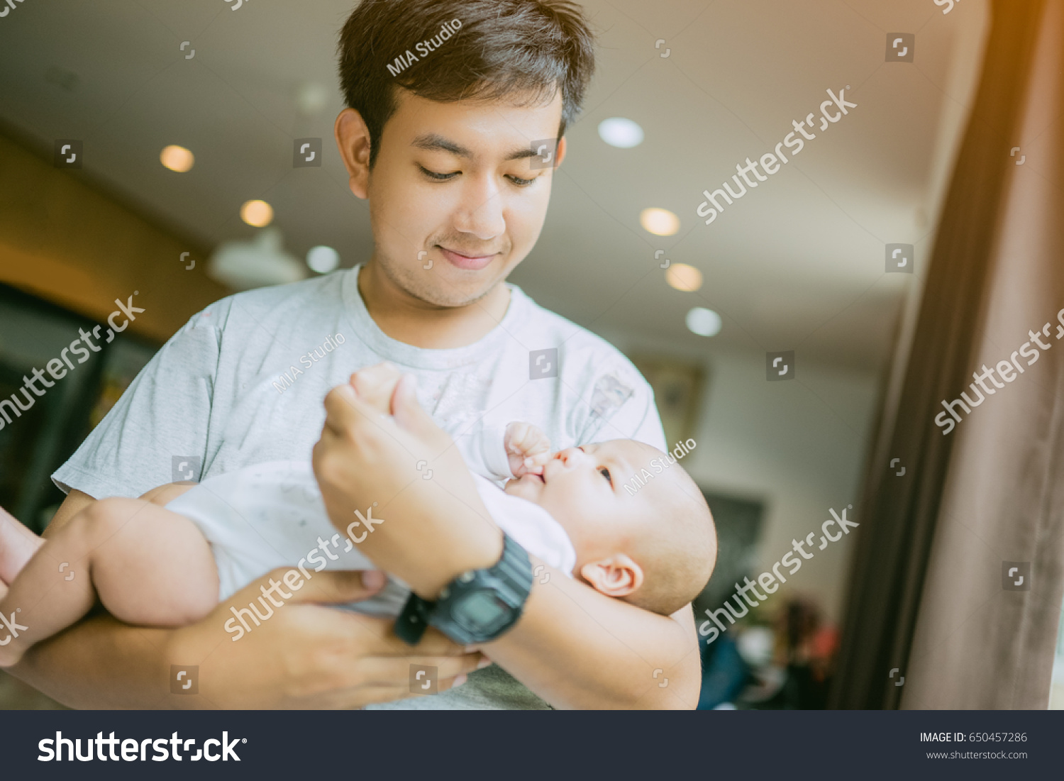 Portrait of young asian father holding his newborn baby son at home.