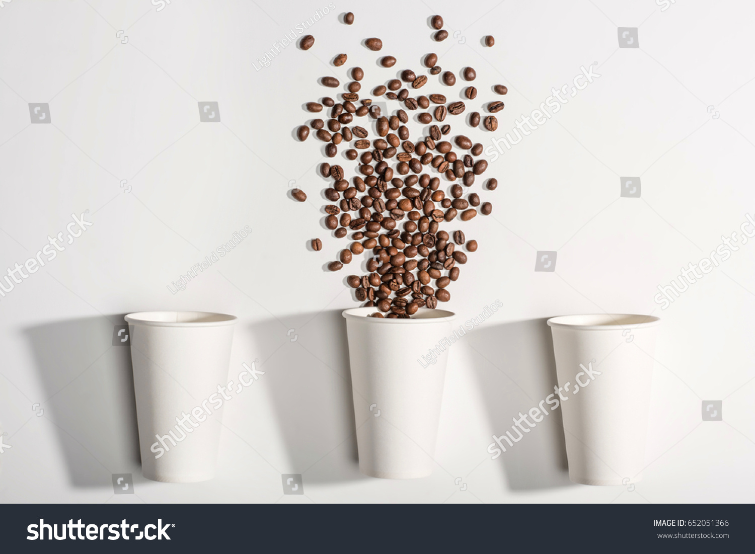 top view of white disposable paper cups with coffee beans isolated on white