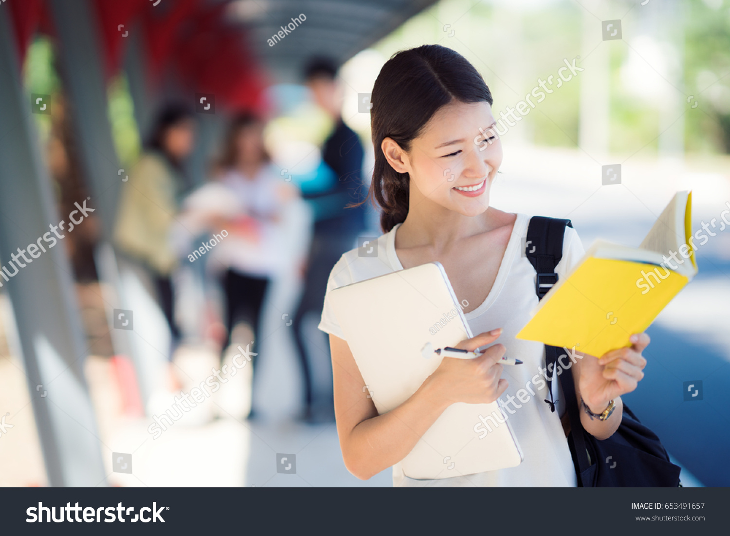 Asian lady student in university walking in walk way and carry computer notebook and bag on hand