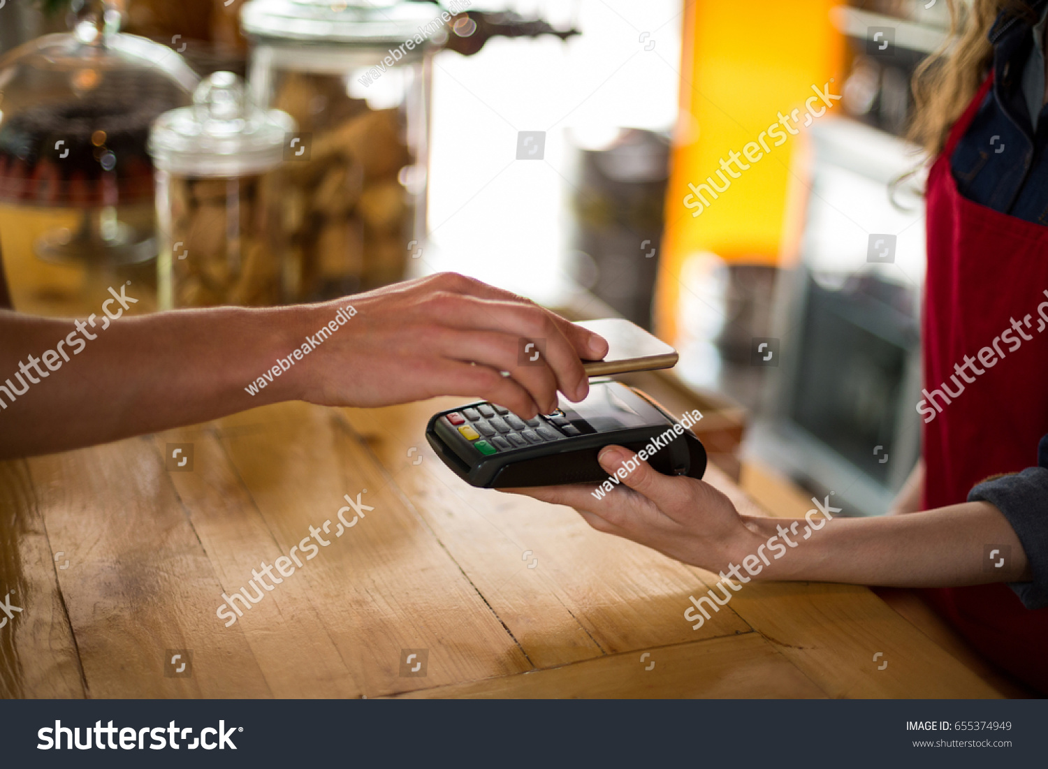 Man paying bill through smartphone using NFC technology in cafe