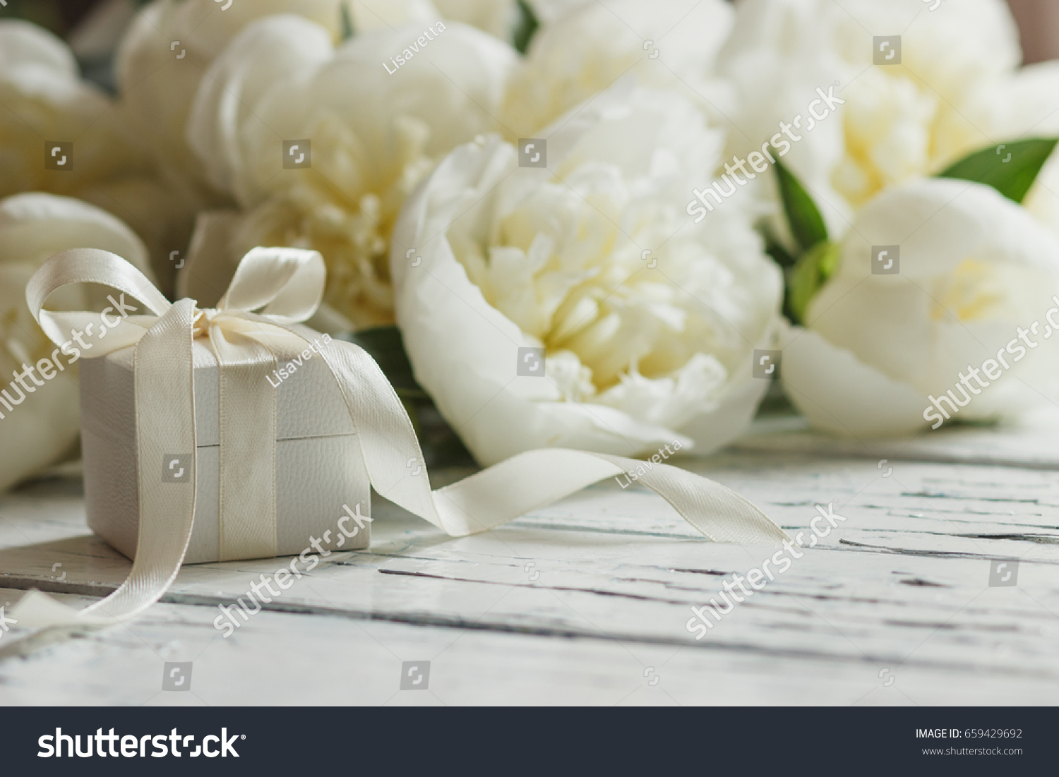 Bouquet of white peonies and present box on the wooden table  soft focus background