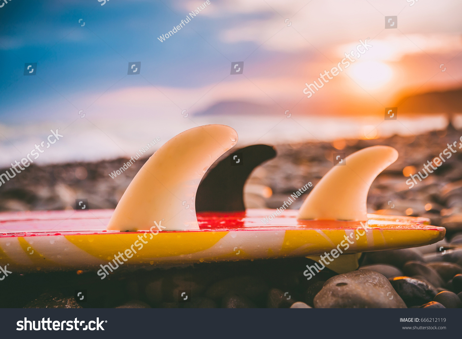 Surfboard on a beach with sunset or sunrise colors.
