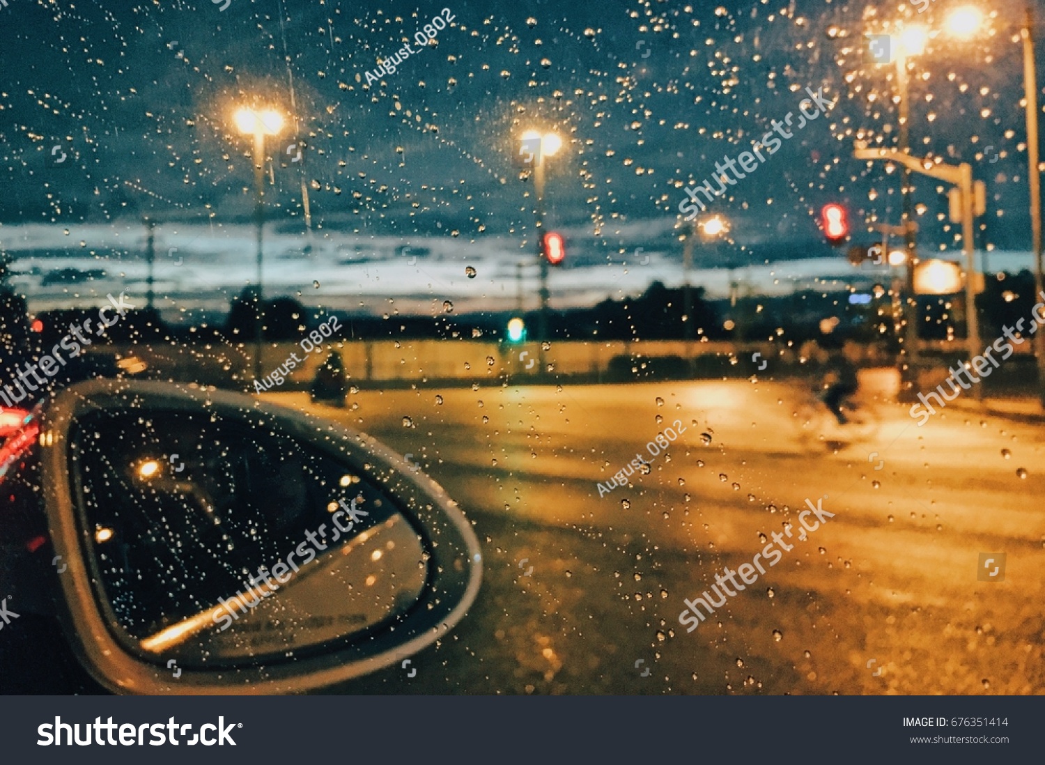 Rain drops on car window with road light bokeh City life in night in rainy season abstract background water drop on the glass night storm raining car driving concept.