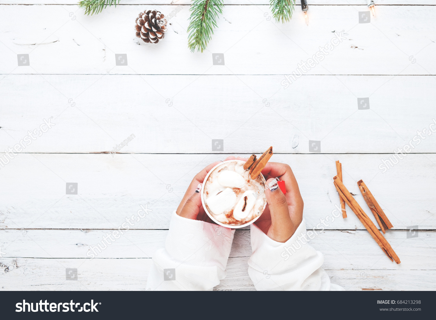 Christmas background - Girl hand holding cup of hot chocolate on white table with rustic decoration and copy space flat lay top view. vintage color tone style.