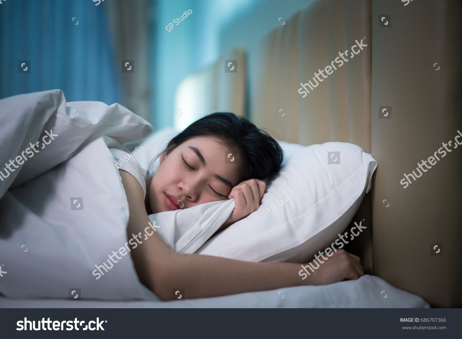 Asian woman sleeping in a bed in a dark bedroom