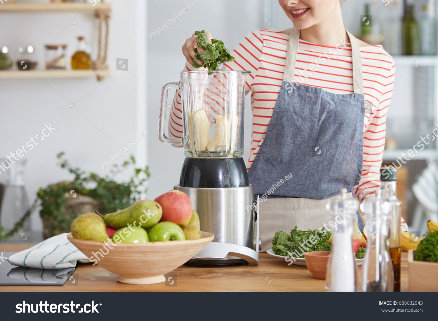Woman making healthy smoothie with bananas and kale