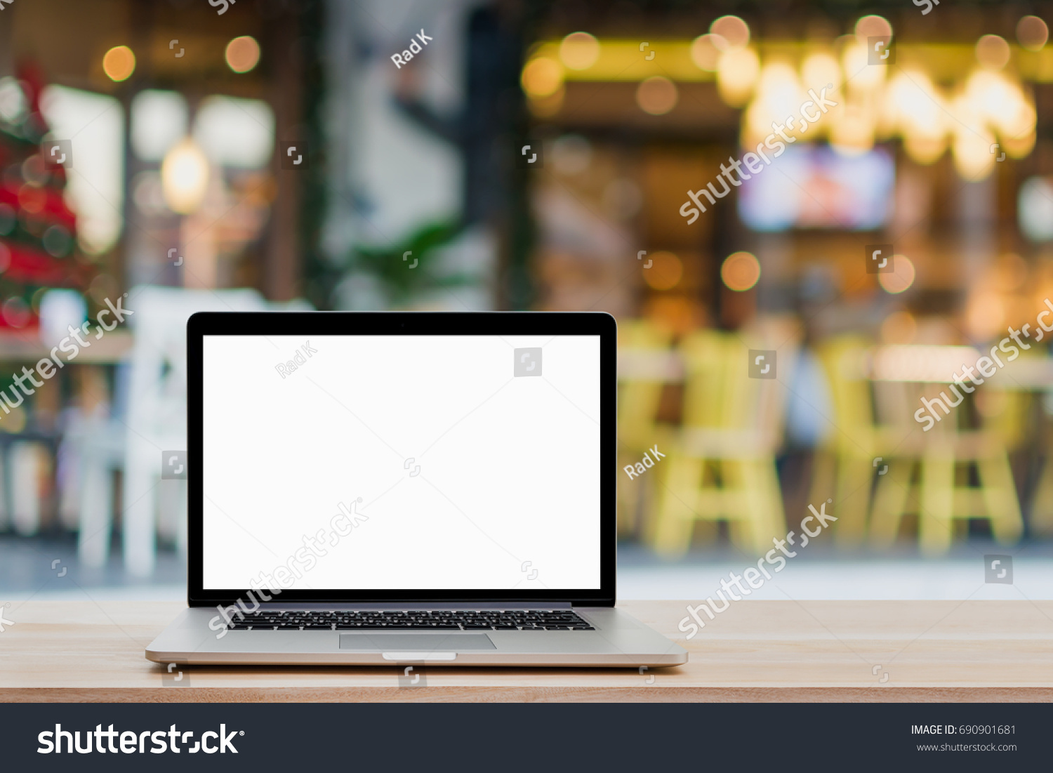Laptop with blank screen on wood table and coffee shop background.