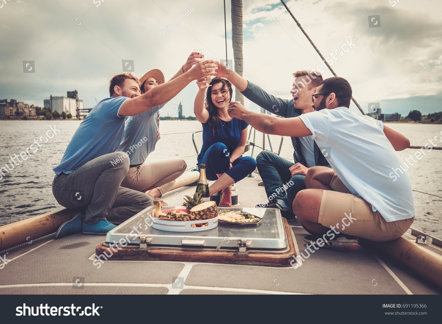 Happy friends eating fruits and drinking on a yacht