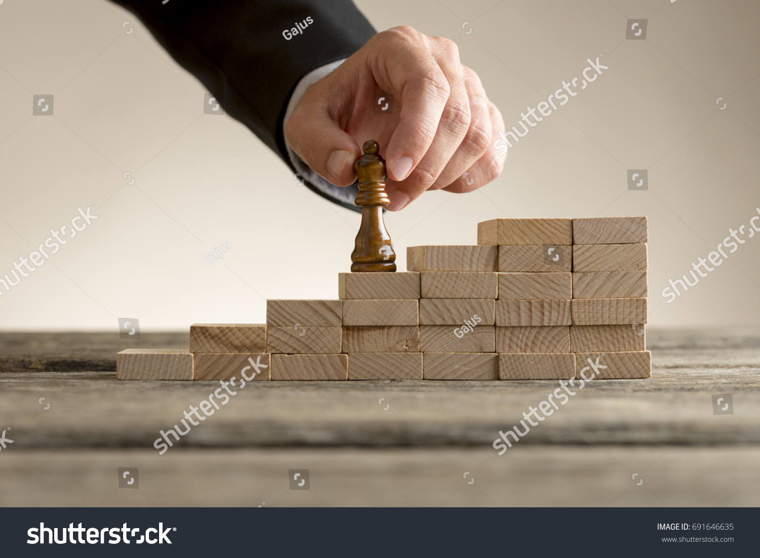 Business success and promotion concept with a businessman moving the queen piece up a series of steps formed by building blocks.