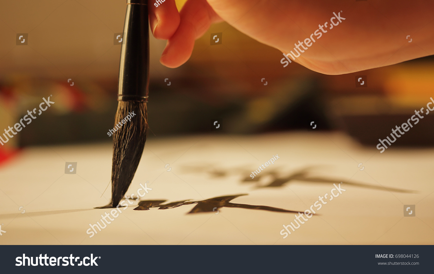 Close up on hand holding brush while writing calligraphy