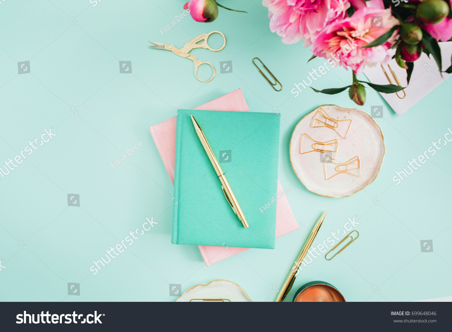 Flat lay home office desk. Female workspace with pink peony flowers bouquet  golden accessories  pink and mint diary on mint background. Top view feminine background.