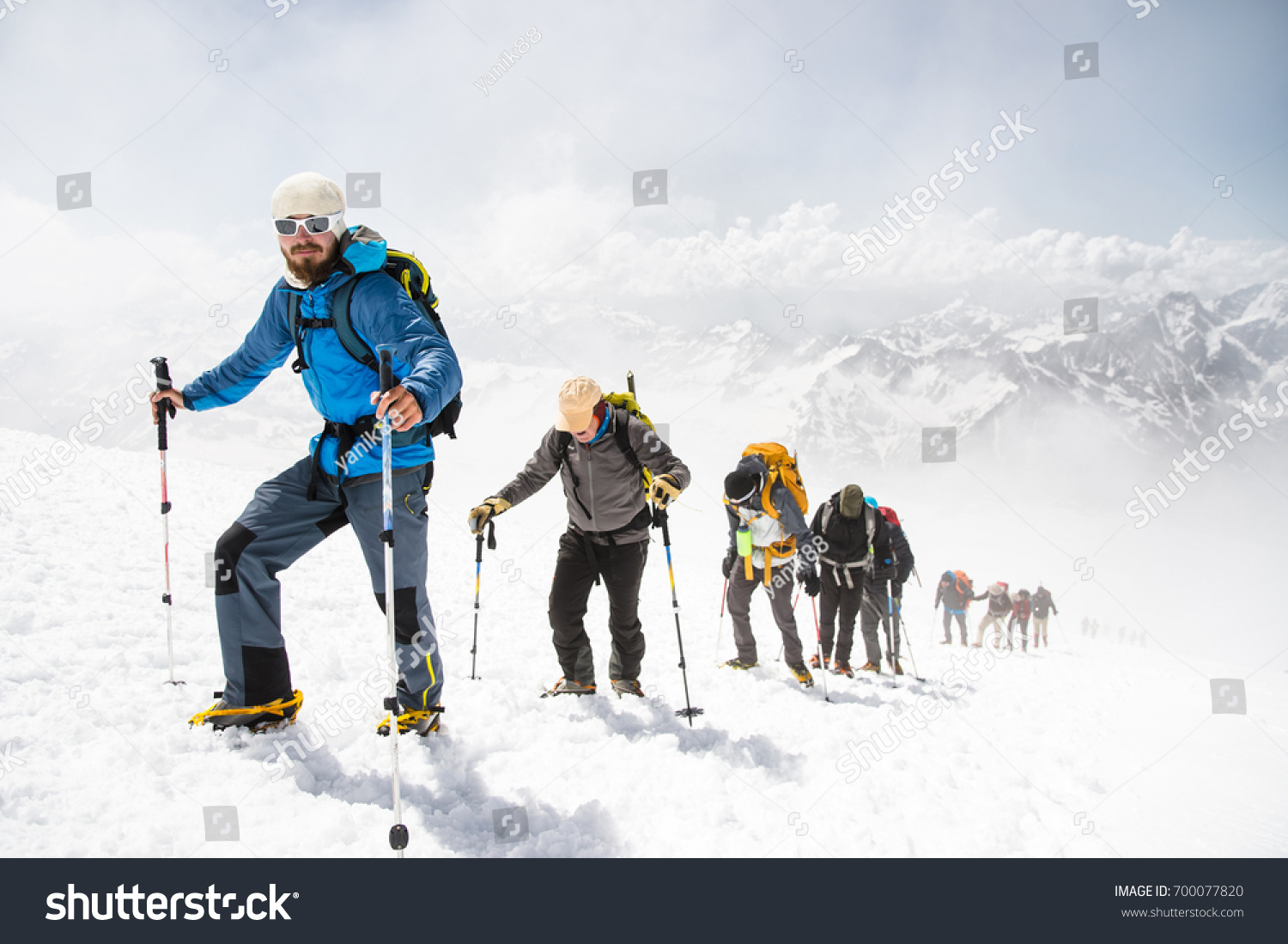A group of mountaineers climbs to the top of a snow-capped mountain