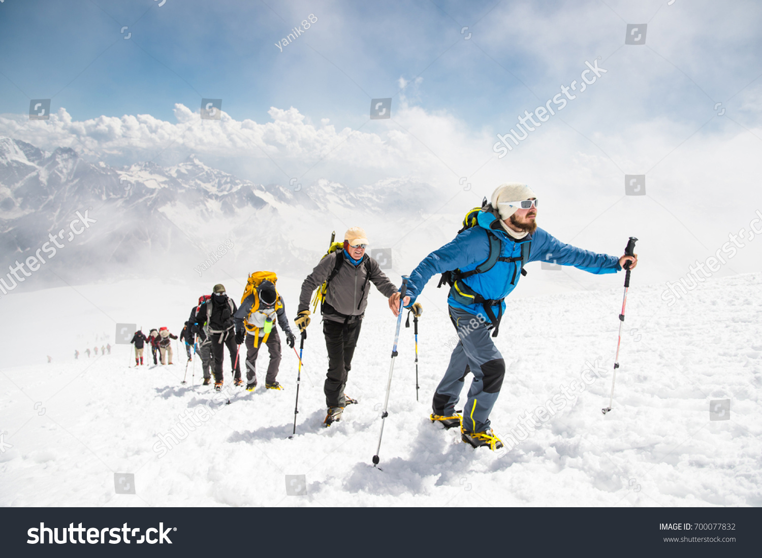 A group of mountaineers climbs to the top of a snow-capped mountain