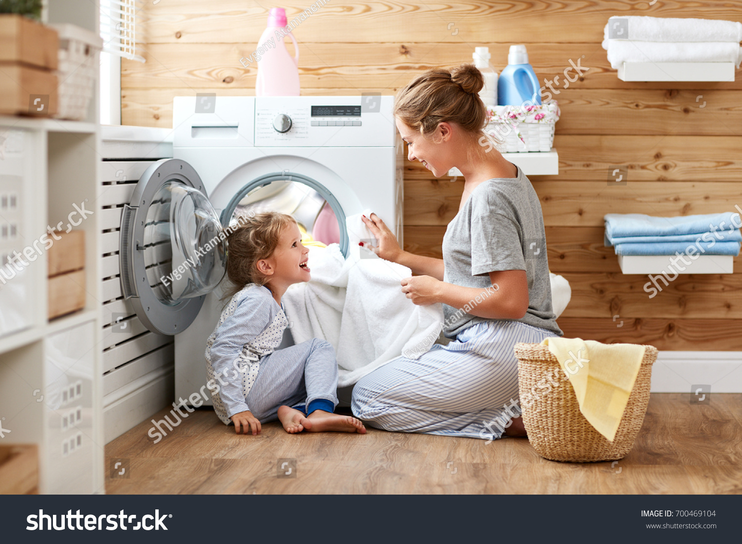 Happy family mother housewife and child daughter in laundry with washing machine 
